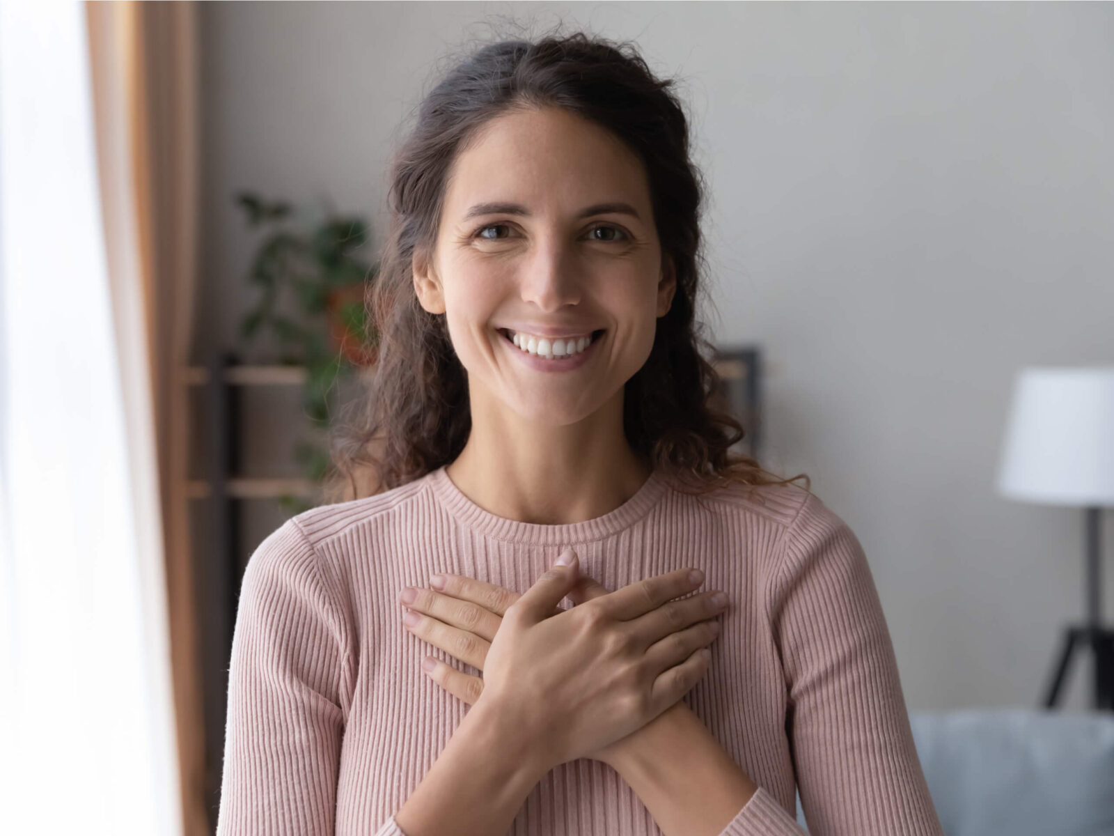 Portrait of happy millennial female volunteer holding folded hands on chest,