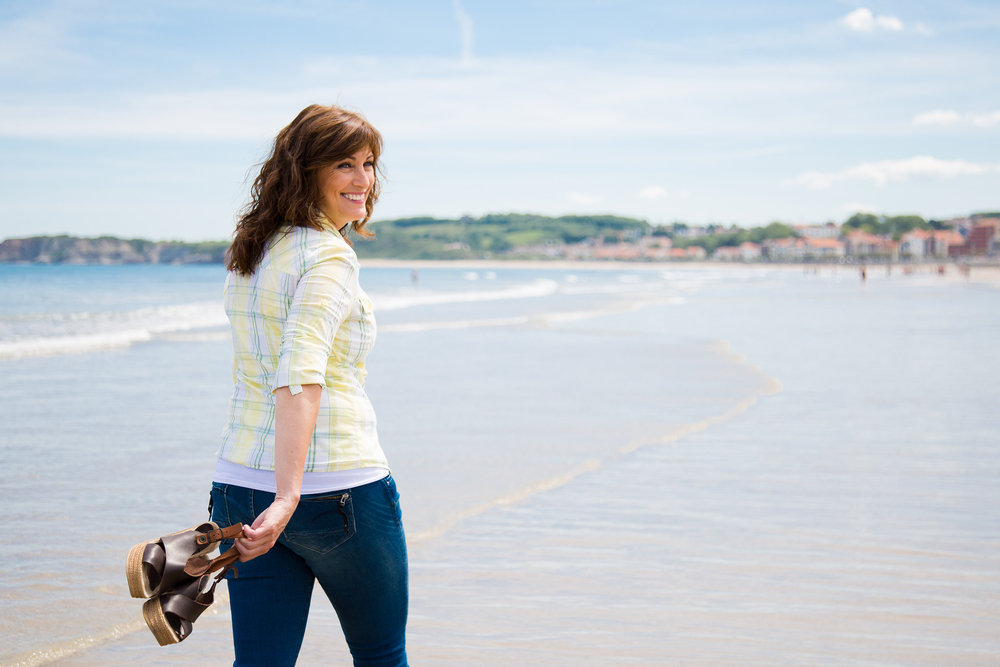Attractive And Happy Middle Aged Woman Walking Along The Seashore