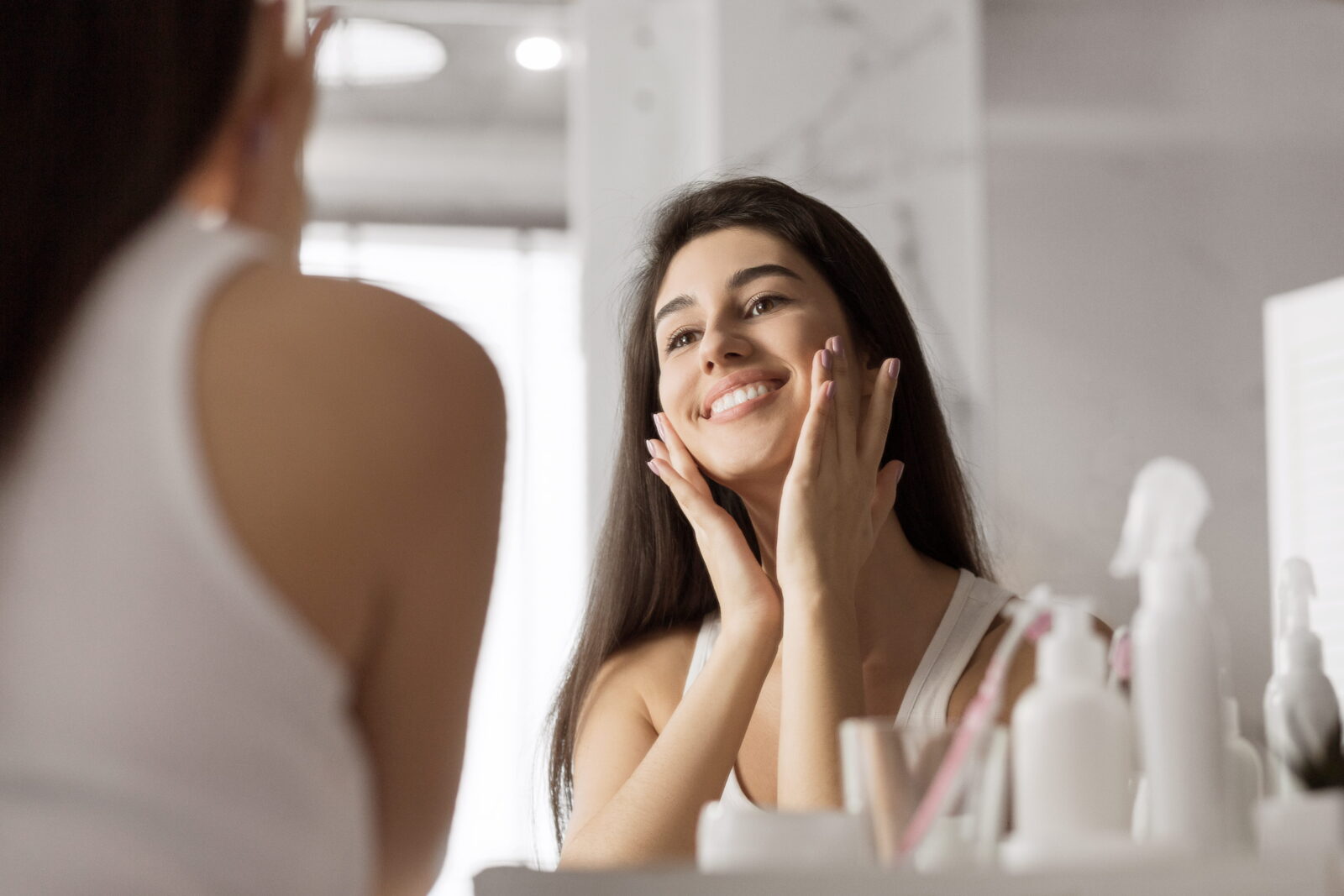 A woman smiling in the mirror after healing from a Facelift