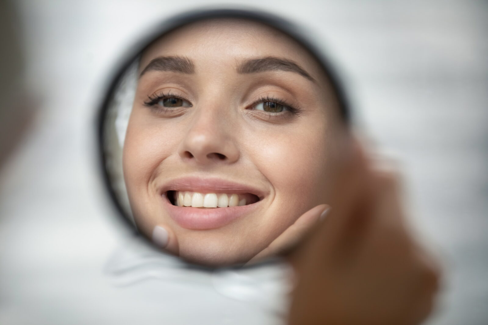 woman looking in the mirror after a rhinoplasty