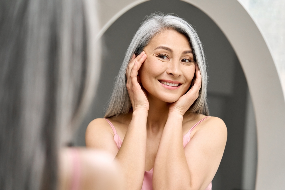 woman smiling in the mirror after receiving a Juvederm treatment
